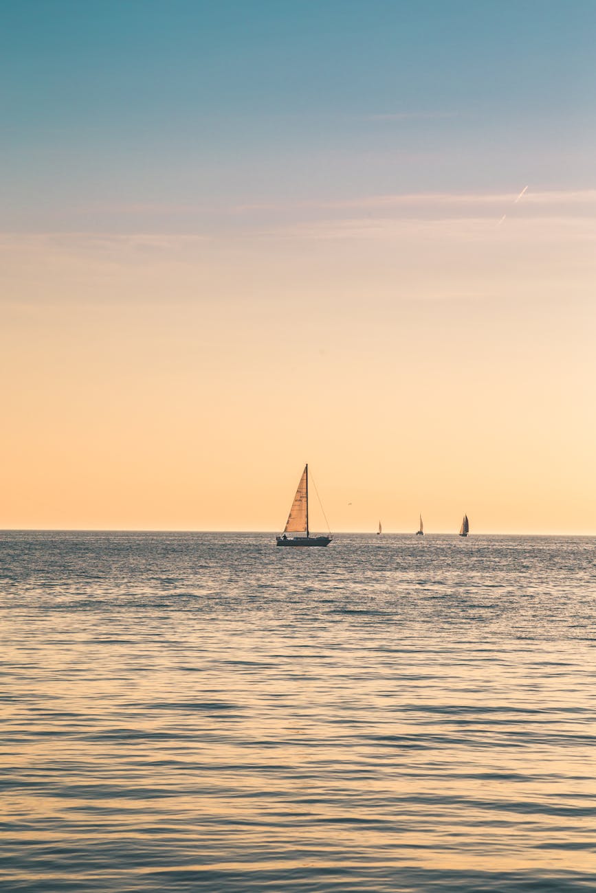 beige sailboat under clear skies